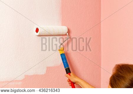 The Female Hands Of The Painter Paint The Pink On The Wall With White Paint With A Paint Roller.