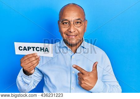 Middle age latin man holding captcha message paper smiling happy pointing with hand and finger 