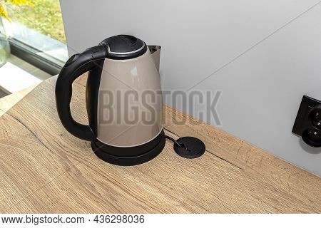 An Electric Kettle Standing On The Countertop On The Kitchen Cabinets, Visible Hole In The Table Top