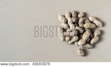 Inshell Peanuts And Scattered Inshell Peanuts On A Light Brown Background Top View. Walnut Peanut Ko