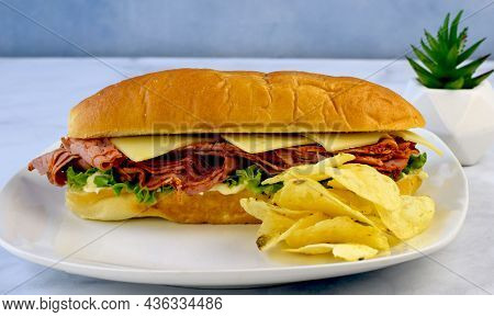 Shaved Pastrami Sandwich Top With Swiss Cheese And A Side Of Potato Chips