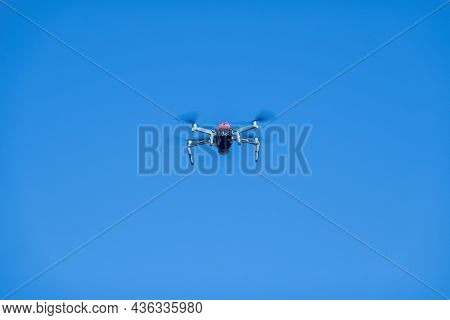 A Drone In Mid Flight Just After Take Off With Its Blades Whirring Against A Clear Blue Sky