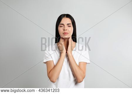 Young Woman Doing Thyroid Self Examination On Light Background