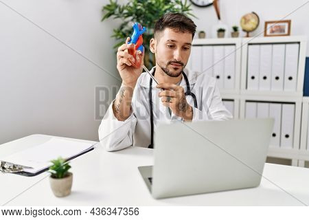 Young hispanic man wearing doctor uniform having teleconsulting at clinic