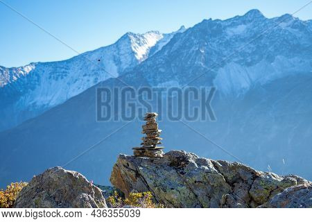 Hiking In Central Switzerland. A Cairn Marking A Footpath, High Mountains In The Background