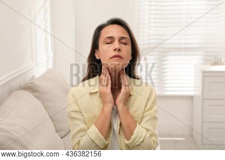 Mature Woman Doing Thyroid Self Examination At Home