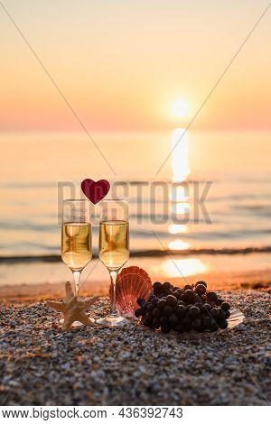 A Romantic Evening At The Sea For A Couple In Love. A Small Heart Between Two Glasses Of Champagne. 