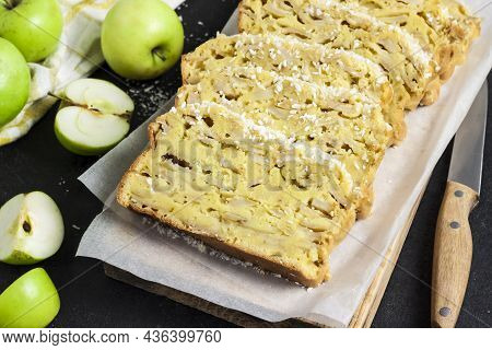 Sliced Apple And Coconut Oaf Cake On Wooden Cutting Board On Dark Background