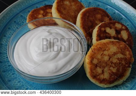 Breakfast Cheesecakes Curd Pancakes A Few Five Pieces Lie On A Large Blue Dish Plate With White Sauc