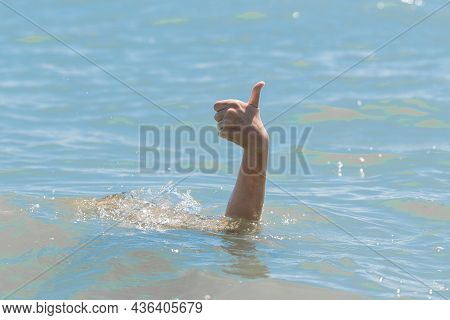 Hand From Under The Water Of A Drowning Girl Shows Class With A Thumb Up. Help And Urgent Rescue Of 
