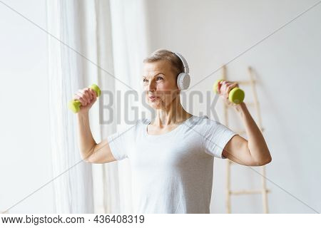Portrait Of Smiling Senior Woman Exercising Fitness With Dumbbells At Home. Mature Female Build Up B