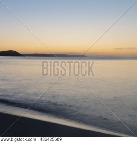 Beautiful Sunrise Over Pentewan Sands In Cornwall With Pastel Sky And Long Exposure Ocean