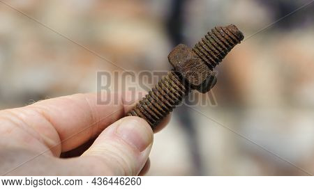 Old Rusty Bolt, Iron Rod With Screw Threads, In Hand. Rusted Mechanical Components. Holding Threaded