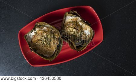 Top View Steamed Curry Fish In Banana Leaf Cups Or Thailand Name Hor Mok Pla. Is Placed On A Red Pla