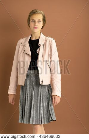 Happy Girl Whirling Against Brown Background. Joyful Attractive Brown Haired Teen Girl Dressed Pink 