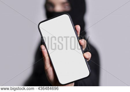 Muslim Woman In Hijab Holds A Smartphone With Empty Screen. Arab Woman In Traditional Clothing Holdi