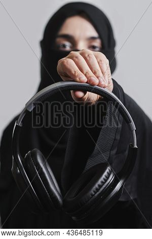 Muslim Woman In Traditional Hijab Clothing Holding Black Wireless Headphones