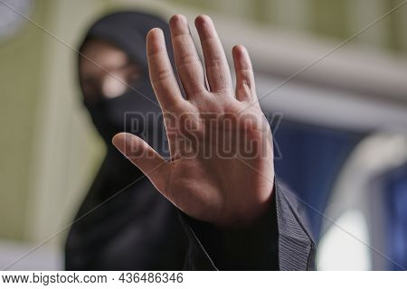 A Muslim Woman In Traditional Black Clothing Nikab Showing Stop Hand Gesture. Role Of Women In Islam