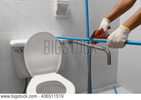 Worker Installing Floating Pipeline On The Wall In The Old Bathroom