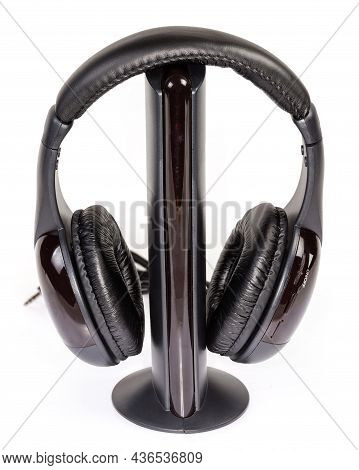 Black Modern Wireless Full Size Closed-back Headphones Hanging On Its Emitter On A White Background