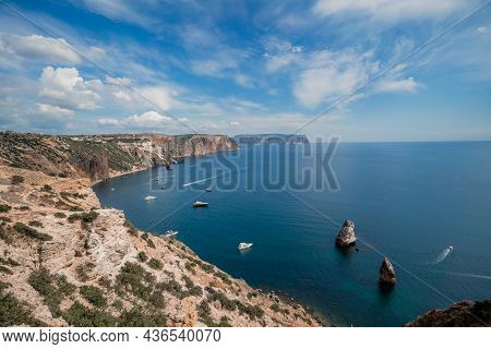 Two Rocks Stick Out Of The Water In The Middle Of The Turquoise Sea. Scenic Ocean View. Speed Boat S