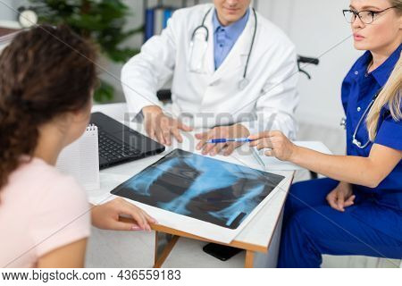 A Doctor And A Lady Doctor Are Discussing An X-ray Of Their Patients Lungs.