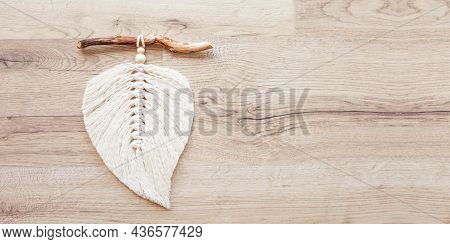 Macrame Leaf  In Natural Color And Thread Windings Lying On A Wooden Table. Cotton Rope Decor Macram