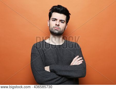 young handsome man posing over orabge background