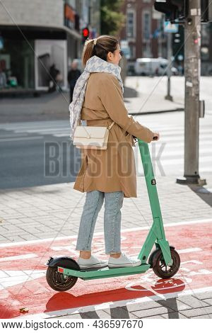 traffic, city transport and people concept - woman riding electric scooter along red bike lane with signs of bicycles and two way arrows on street