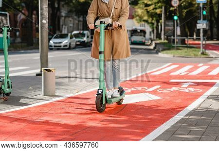 traffic, city transport and people concept - woman riding electric scooter along red bike lane with signs of bicycles and two way arrows on street
