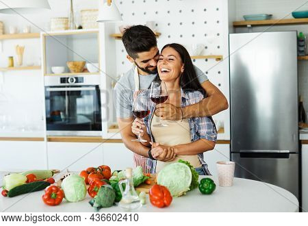 Happy Young Couple Preparing Food Having Fun Dringking Wine In Kitchen