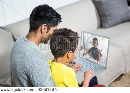 Biracial boy with father using laptop for video call, with elementary school pupil on screen. communication technology and online education, digital composite image.