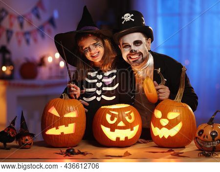 Happy Family Father And Daughter In Halloween Costumes With Glowing Jack-o-lantern Celebrating All H