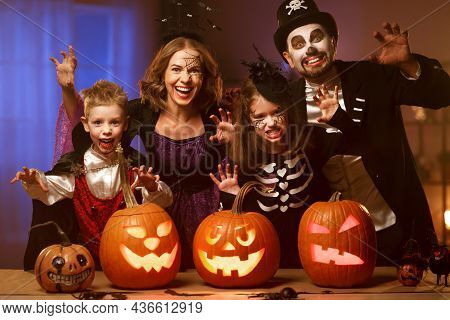 Young Family Mother Father And Children In Halloween Costumes Celebrating All Hallows Eve At Home