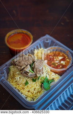 Roasted Meat Served With Rice And Chillies Tamarind Sauce And Curry Gravy In A Take Out Container. M