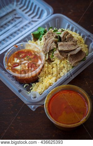 Roasted Meat Served With Rice And Chillies Tamarind Sauce And Curry Gravy In A Take Out Container. M