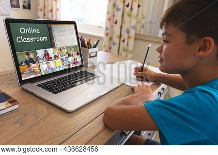 Smiling caucasian boy using laptop for video call, with diverse elementary school pupils on screen. communication technology and online education, digital composite image.