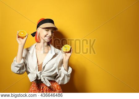 Beautiful Young Woman With Bright Dyed Hair Holding Orange Halves On Color Background