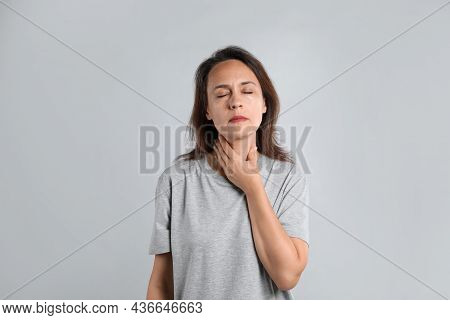 Mature Woman Doing Thyroid Self Examination On Light Background