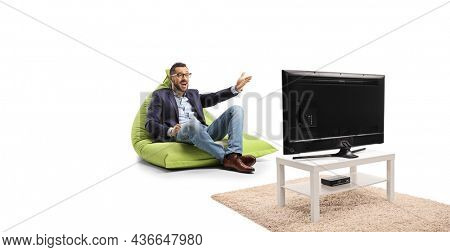 Man sitting on a green bean bag chair, gesturing with hand and watcing tv isolated on white background