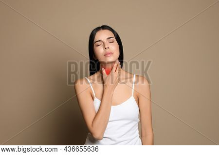 Young Woman Doing Thyroid Self Examination On Beige Background