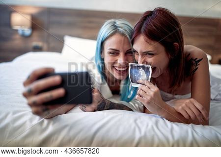 Joyful lesbian couple announcing a pregnancy test results together