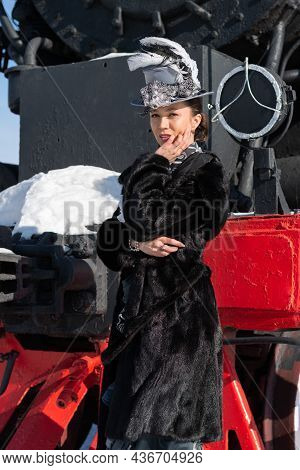 Girl Dressed As A Noblewoman Of The 19Th Century Near A Steam Locomotive. Russian Winter