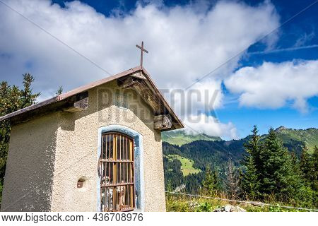 Small Chapel In Front Of A Mountain Landscape. La Clusaz, France