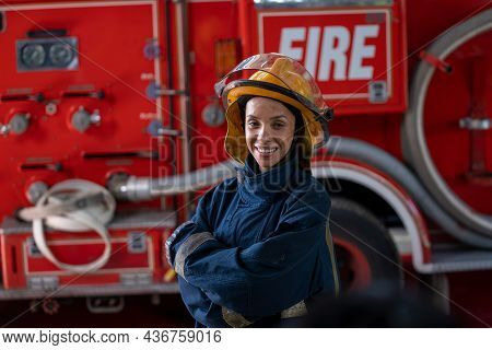 Portrait Of Firewoman Wearing Firefighter Turnouts While Standing At Fire Station Near Fire Engine.