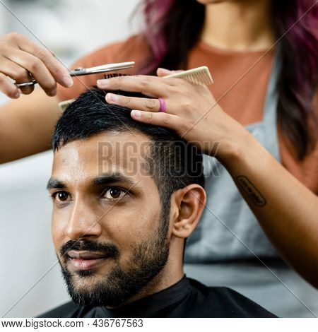 Man getting a haircut from a hair stylist at a barber shop