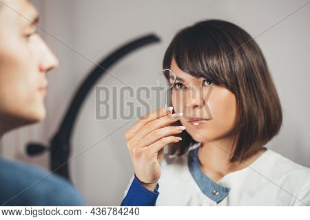 Doctor Ophthalmologist Holding Lenses To Check Patient's Vision. Focus On Lens, Face Is In Soft Focu