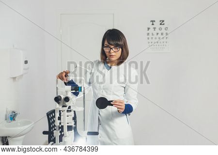 Doctor Ophthalmologist Holding Lenses To Check Patient's Vision. Focus On Lens, Face Is In Soft Focu