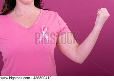 Midsection of caucasian woman in pink tshirt with ribbon and clenched fists. breast cancer positive awareness campaign concept digitally generated video.