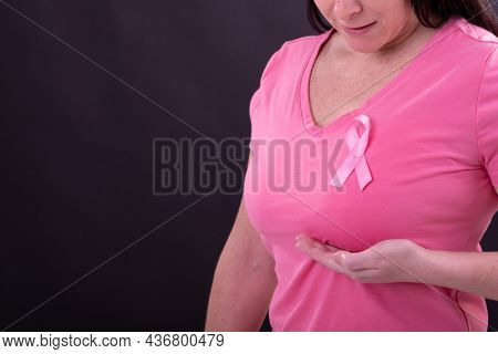 Midsection of caucasian woman in pink tshirt with pink ribbon gesturing. breast cancer positive awareness campaign concept digitally generated video.